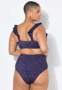 Set di bikini a vita alta con stampa leopardata in viola e navy. Il top ha spalline arricciate e il materiale sembra liscio ed elasticizzato.