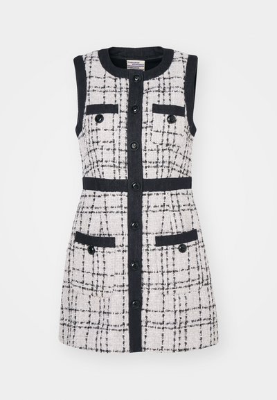Robe sans manches en tweed texturé de couleur écru avec un motif à carreaux noir. Présente des boutons noirs, deux poches avant et une coupe ajustée.