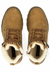 Bottines en daim marron avec une doublure blanche duveteuse, quincaillerie en métal pour les lacets et accents à motifs près de la cheville. Présentent un bout arrondi et une semelle en caoutchouc.