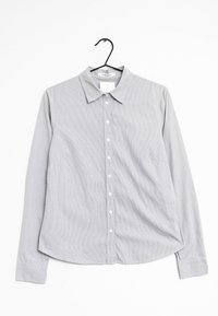 Chemise à rayures grises et blanches avec un col, des manches longues et une poche poitrine. Fabriquée dans un tissu léger et texturé.