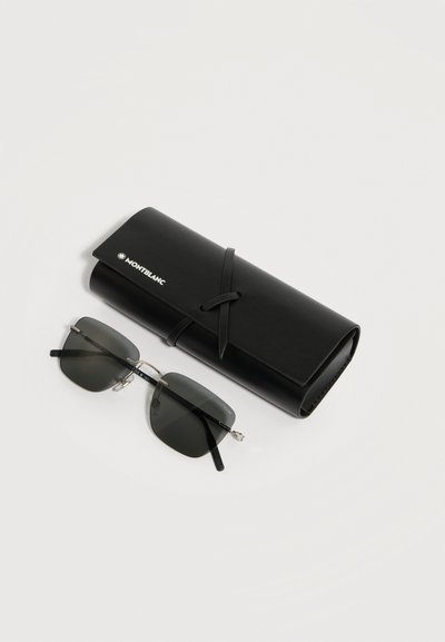Μαύρα ορθογώνια γυαλιά ηλίου με σκούρους φακούς δίπλα σε κυλινδρική μαύρη δερμάτινη θήκη Montblanc σε λευκό φόντο.