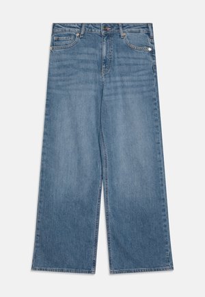 Jean large en denim bleu avec fermeture devant par bouton et zip, deux poches avant et passants pour ceinture sur fond uni.