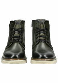 Botas de tobillo de cuero verde con cordones negros, punta redondeada y costuras decorativas. Presenta una suela blanca en contraste y un cierre con cremallera.