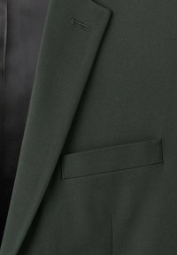 Dunkelgrünes Sakko aus strukturiertem Stoff mit einer einzigen Brusttasche, maßgeschneiderten Revers und einem kontrastierenden schwarzen Innenfutter.