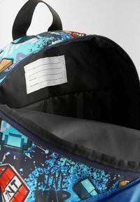 Mochila con un estampado gráfico vibrante que presenta colores azul y negro. En el interior, se puede ver una etiqueta para el nombre y los datos de contacto.