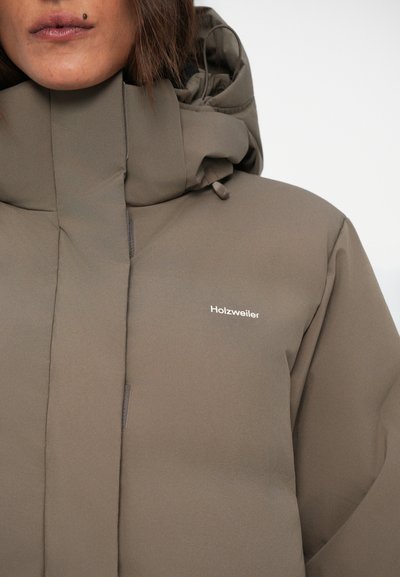 Veste rembourrée marron avec un col montant et une capuche intégrée. Présente une fermeture éclair et un petit logo sur la zone gauche de la poitrine.