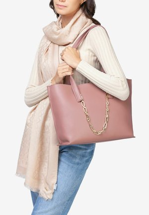 Roze leren tote bag met gouden kettingaccent, rechthoekige vorm, gladde textuur, gecombineerd met een lichte sjaal en een geribbelde top met lange mouwen.
