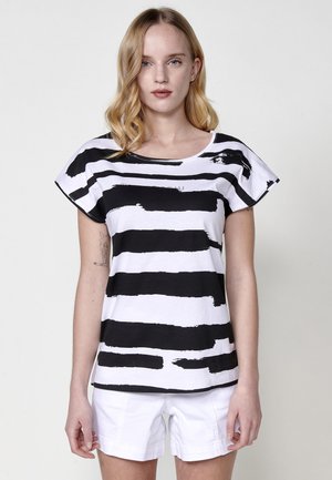 T-shirt à rayures noires et blanches avec un col rond, des manches courtes et une coupe décontractée, arborant un motif de coups de pinceau sur le tissu.