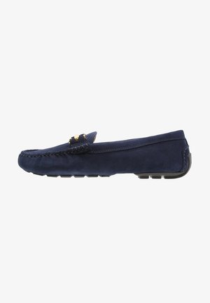 Mocassins en daim bleu marine avec un motif cousu, agrémentés de ferrures dorées. Semelle plate avec détails en caoutchouc antidérapant. Forme classique et épurée.