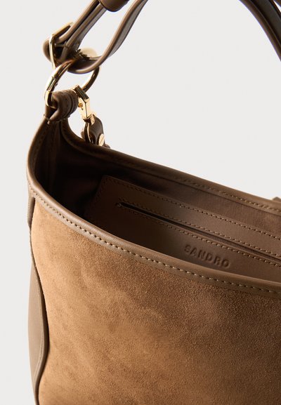 Καστανό σουέντ τσάντα χειρός με δερμάτινες λεπτομέρειες, χρυσά μεταλλικά στοιχεία και ορατή εσωτερική τσέπη με φερμουάρ και ανάγλυφη ετικέτα "SANDRO".