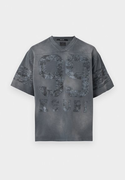 Σκούρο γκρι κοντομάνικο πουκάμισο με σχήμα V στον λαιμό, με μεγάλο φθαρμένο κείμενο "99" και "KSUBI" στο μπροστινό μέρος, καθώς και δύο ρίγες στα μανίκια.