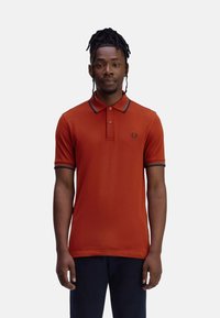 Rode korte mouwen polo shirt met een drieknoopsluiting, contrasterende kraagafwerking en een klein logo op de linker borst. Glad gebreide stof.