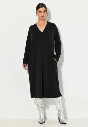 Zwart lange mouw jurk met V-hals, met zijzakken en een losse fit. Gecombineerd met glanzende zilveren knielange laarzen.