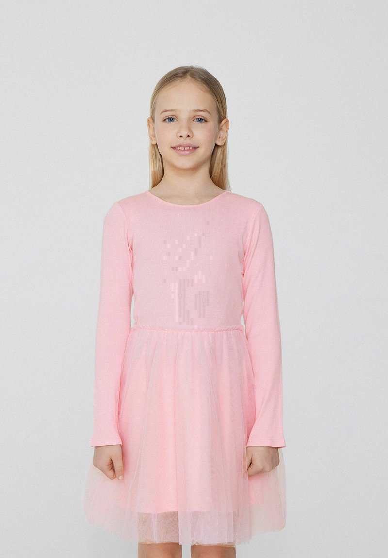 Robe à manches longues avec un corsage en rib au rose et une jupe en tulle superposée, créant une apparence douce et texturée.