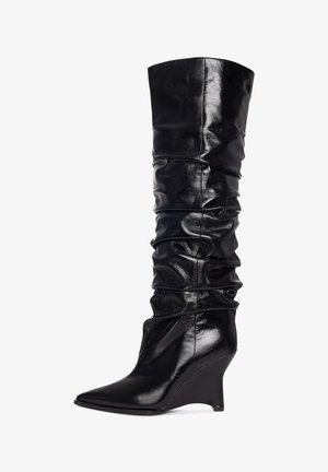Botas de cuña negras hasta la rodilla con un acabado brillante de charol. Diseño holgado y puntera afilada, con textura recogida a lo largo del caño.