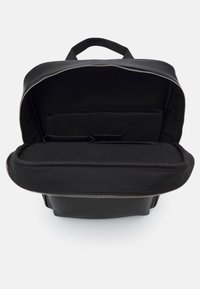 Zaino nero con chiusura con zip, compartimenti interni per l'organizzazione e una texture liscia. Anche l'imbottitura è nera.