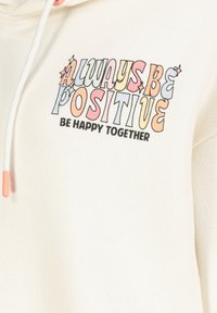 Cremiger Kapuzenpullover mit einem Frontgrafikdesign, auf dem "ALWAYS BE POSITIVE" in bunten Buchstaben steht; verfügt über einen Kordelzug mit pinken Enden.