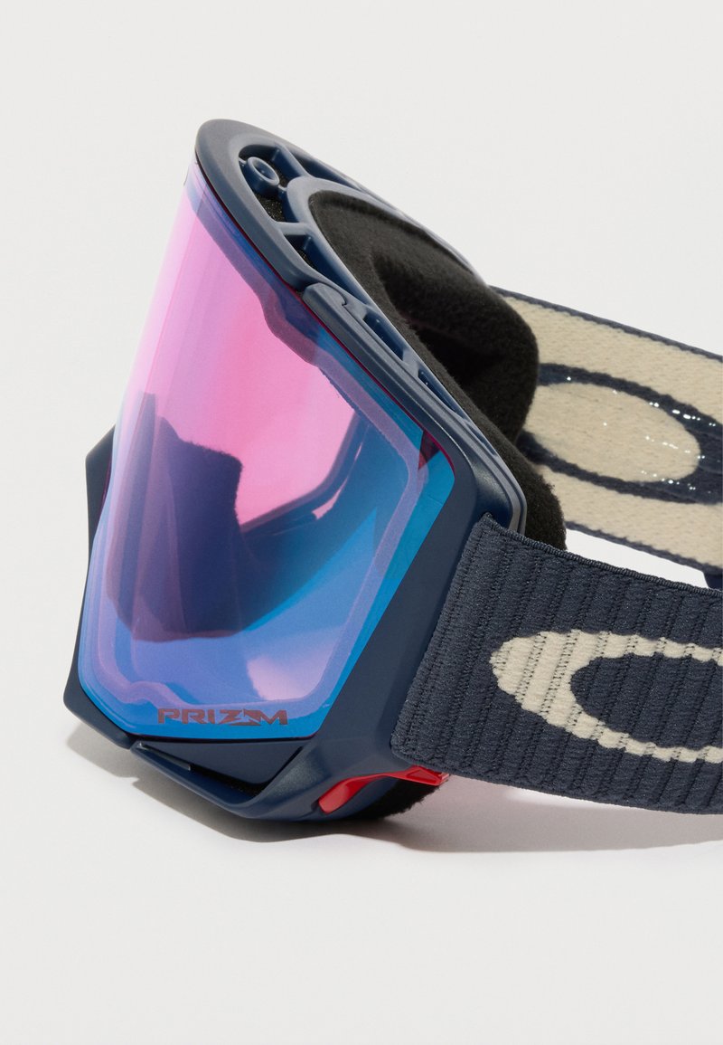 Blå ski-briller med en stor lys pink-tonet linse, blød sort skumpolstring og et blåt bånd med et lysefarvet logo.