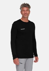 Zwart langetermijnshirt van lichtgewicht stof met een ronde halslijn en subtiel logo op de linkerkant van de borst. Soepele textuur, aansluitend ontwerp.