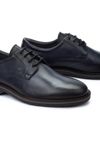 Chaussures en cuir noir avec une finition lisse, bout arrondi et lacets contrastés. Présentent un logo discret sur le côté et une semelle texturée.