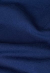 Navyblauwe ribbelstof met een zachte textuur, die subtiele golven en plooien vertoont, wat flexibiliteit en rek aangeeft.