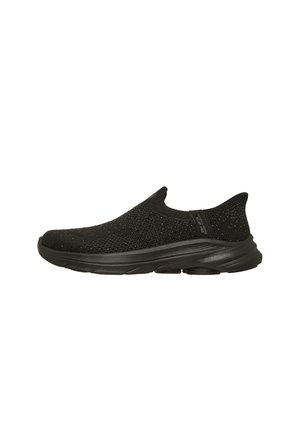 Zapatilla deportiva negra tipo slip-on con parte superior de tejido de punto, suela acolchada y marca "Skechers" en la lengüeta lateral.
