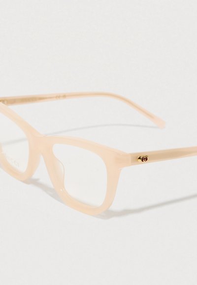 Óculos em tom pêssego com uma armação de plástico translúcido, em forma retangular, apresentando lentes transparentes e um pequeno detalhe dourado na ast. 