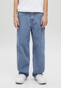 Jeans in denim blu chiaro, a taglio morbido e dritto. Presentano cuciture visibili e tasche laterali. Indossati con sneakers bianche.