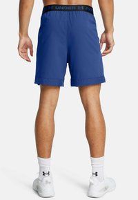 Mėlynos sportinės šortai su juodu juosmeniu, ant kurio užrašas "UNDER ARMOUR". Lengvas audinys, perforuotas apvadas ir lygus paviršius.