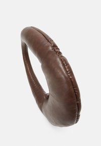 Cojín circular de cuero marrón con textura suave y detalles fruncidos. Presenta una forma de anillo única, diseñada para la comodidad.