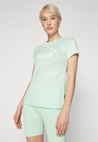 Mätovo zelené tričko s krátkymi rukávmi vyrobené z jemného materiálu má bielu logo Puma na hrudi. Strih je voľný, vhodný na aktívne nosenie.