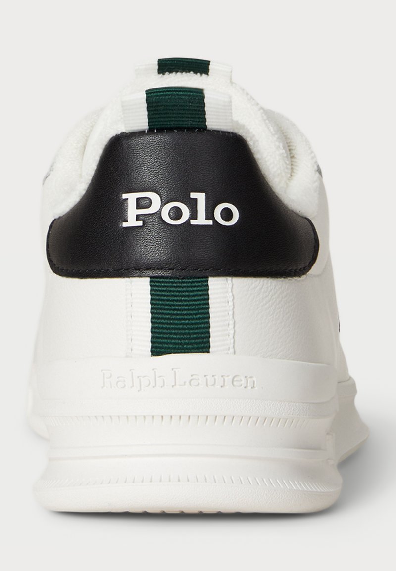 Sneaker bianca con tallone nero e striscia verde. Presenta il logo "Polo" in rilievo e il testo "Ralph Lauren" sul tallone. Texture in pelle liscia.