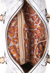 Hvid håndtaske med struktureret finish, der har en livlig orange og lilla leopardmønster foring, en indvendig lynlås lomme og lysebrune detaljer.