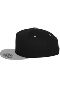 Čierna baseballová čiapka s plochým sivým okrajom, vyrobená z textilného materiálu. Obsahuje vyšívané očká a snapback zapínanie.