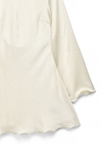 Kremasto obarvan zgornji del iz teksturirane tkanine, z dolgimi zvončastimi rokavi in valovitim robom. Površina ima subtilen vzorec.