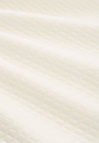 Licht crèmekleurige stof met een textuur en een diamantpatroon. Zachte, gladde textuur en een licht glanzend oppervlak.