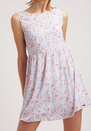 Robe sans manches, longueur au genou, avec taille froncée et motif floral pastel en rose, bleu, jaune et vert sur tissu blanc.