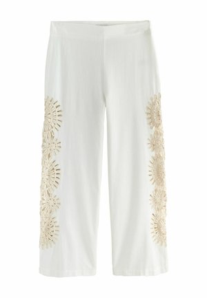 Hvide korte bukser med beige blomsterblondeudskæringsmønstre, der løber lodret langs ydersiden af begge ben.