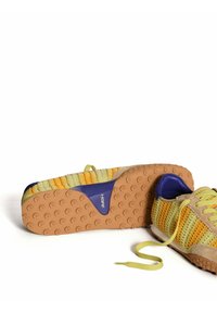 Zapatillas coloridas con parte superior tejida en amarillo y verde, con una puntera de ante beige y una suela de goma texturizada. Incluye cordones verde claro.