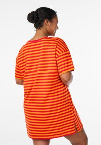 Red and orange striped t-shirt dress with short sleeves, round neckline, and side slits at the hem, made from a soft fabric.