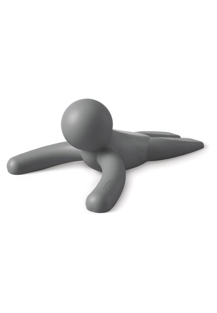 Graue Plastikfigur auf dem Bauch, runder Kopf, ausgestreckte Arme und Beine, glatte Textur, einfaches Design, minimalistische Form.