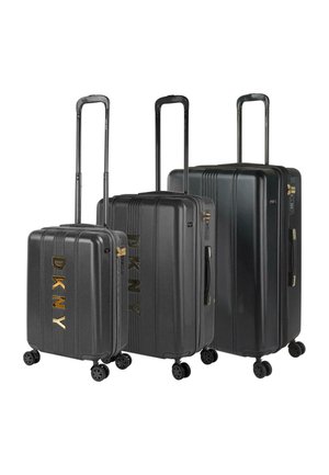 Tres maletas duras negras con ranuras verticales, branding dorado "DKNY", asas telescópicas y cuatro ruedas para mayor movilidad.