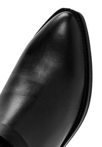 Zwarte leren schoen met een gladde afwerking, puntige neus en slank ontwerp. Heeft een gestikte rand en geen zichtbare hardware of accenten.