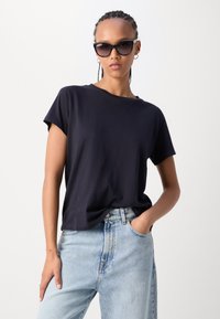 Marineblauw t-shirt met korte mouwen, gemaakt van zacht katoen, gecombineerd met lichtblauwe high-waisted jeans met een relaxte pasvorm en ronde hals.