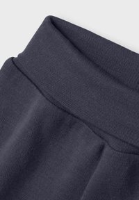 Mörkgrå sweatshirttyg med ribbad midja. Slät textur, medelhårdhet och en närbild som framhäver sömdetaljer.