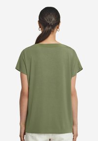 Olivgrön kortärmad T-shirt med en avslappnad passform, rundad halslinje och mjuk textur, med rena kanter och inga synliga mönster.