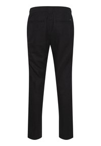 Pantalon noir avec une texture lisse, une taille élastique, deux poches arrière et une conception à jambes effilées. Aucun motif ni matériel visible.