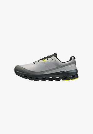 Baskets de sport grises avec une tige en maille texturée, des accents noirs, des détails jaunes et une semelle rembourrée avec des sections découpées pour plus de flexibilité.
