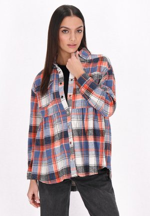 Flannel shirt in red, blue, and black plaid pattern; features button front, two chest pockets, and long sleeves. Cotton fabric, relaxed fit.