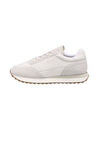 Sneaker en daim gris clair avec des accents blancs, design à lacets, bout rond, semelle texturée et marquage discret sur le talon.